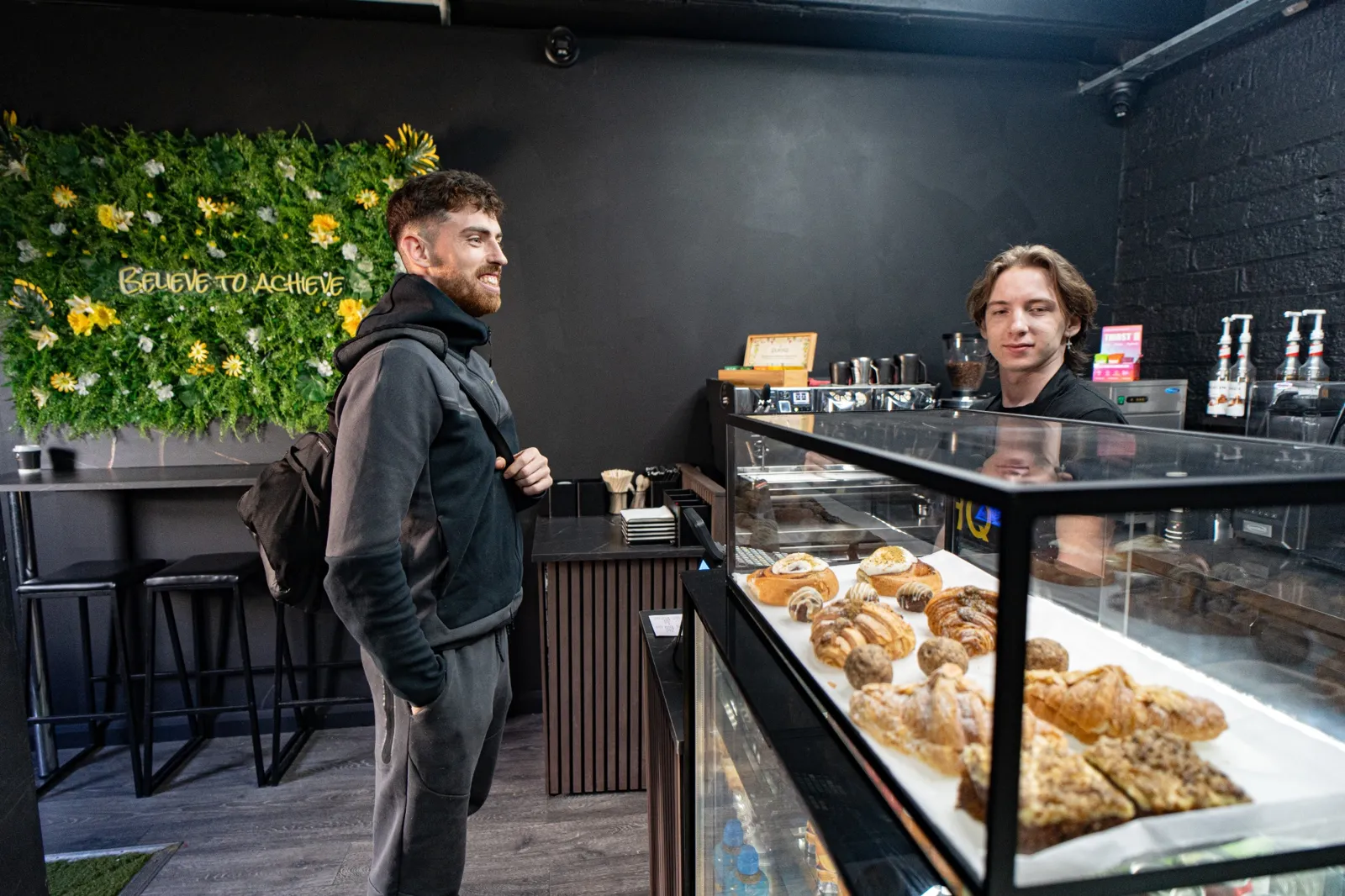 Customer at HQ Brew counter with pastry display